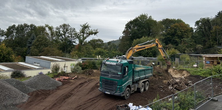 Ein Bagger und ein Kipplaster stehen auf der Baufläche, auf der das neue Zoorestaurant entstehen soll
