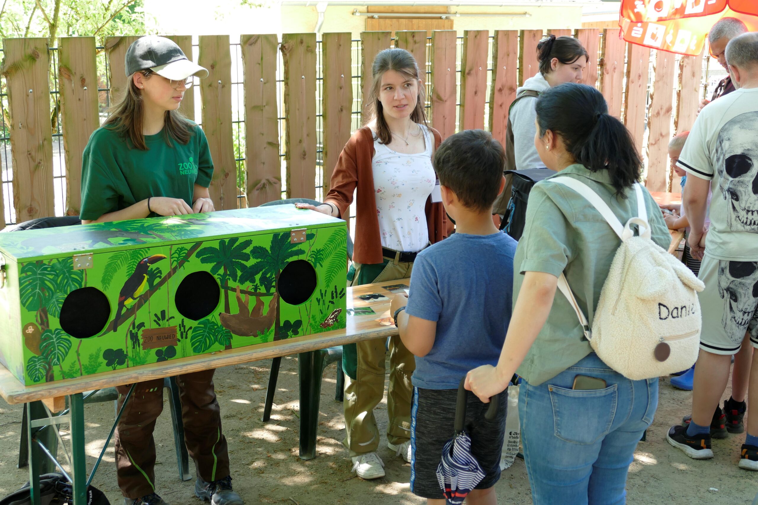 sieben Personen stehen vor einer Bank auf der eine Tastbox zum F&uuml;hlen steht